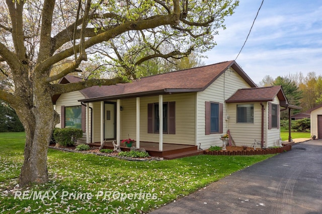 view of front of property featuring covered porch, a shingled roof, and a front yard