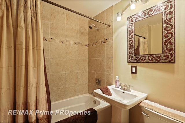bathroom with toilet, shower / tub combo with curtain, and a sink