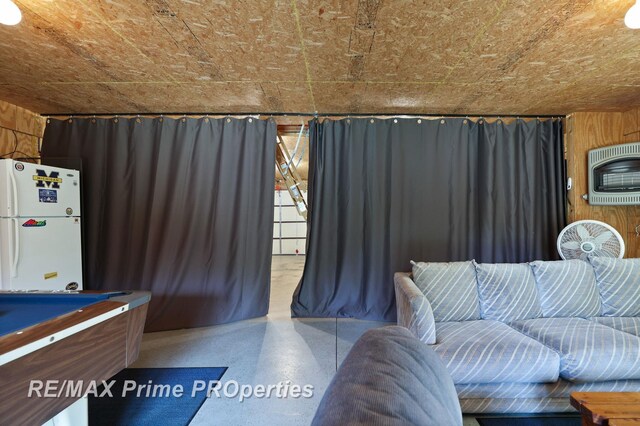 living room featuring speckled floor, heating unit, pool table, and wooden walls