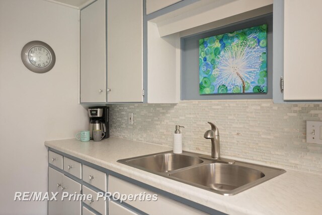 kitchen featuring a sink, light countertops, decorative backsplash, and white cabinets