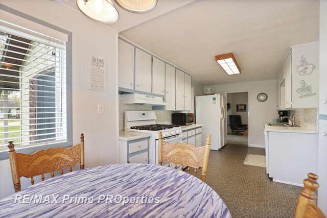 kitchen featuring white appliances, under cabinet range hood, backsplash, and light countertops