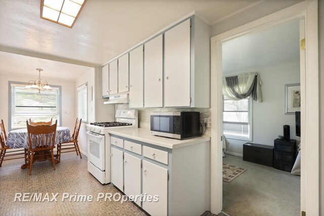 kitchen with white range with gas stovetop, stainless steel microwave, under cabinet range hood, a chandelier, and light countertops