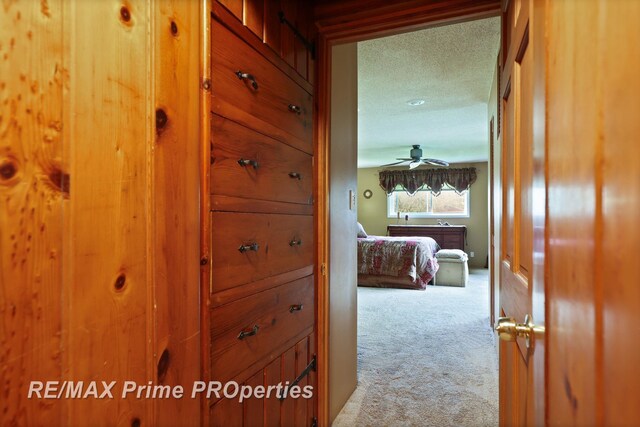 hall featuring carpet floors and a textured ceiling
