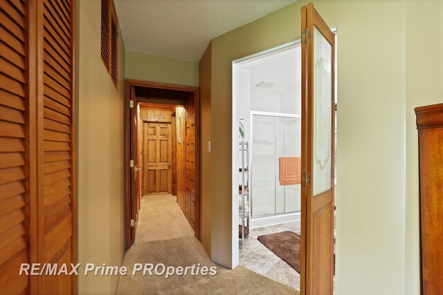 corridor featuring light carpet and a textured ceiling