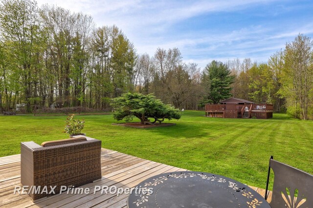 view of green lawn featuring a wooden deck