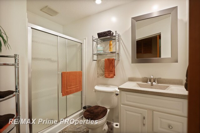 bathroom with a shower stall, toilet, and vanity