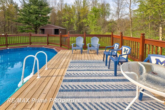 view of swimming pool featuring a wooden deck and an outdoor structure