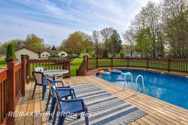 view of pool featuring a wooden deck, a lawn, and outdoor dining space
