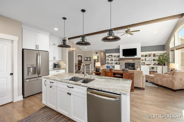 2044 Canopy Dr SW, Byron Center, MI 49315 - kitchen featuring appliances with stainless steel finishes, a sink, a ceiling fan, a stone fireplace, and white cabinets