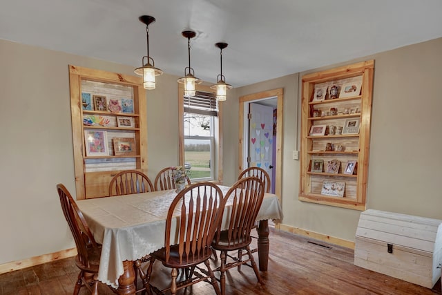 dining space with dark wood-type flooring and baseboards