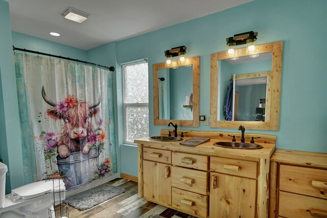 full bath featuring wood finished floors, double vanity, and curtained shower