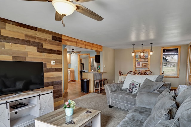 living area featuring a ceiling fan and wood walls
