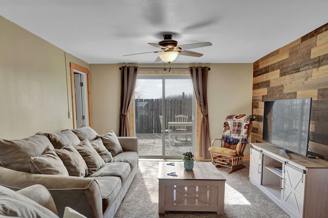 carpeted living room featuring a ceiling fan and wooden walls