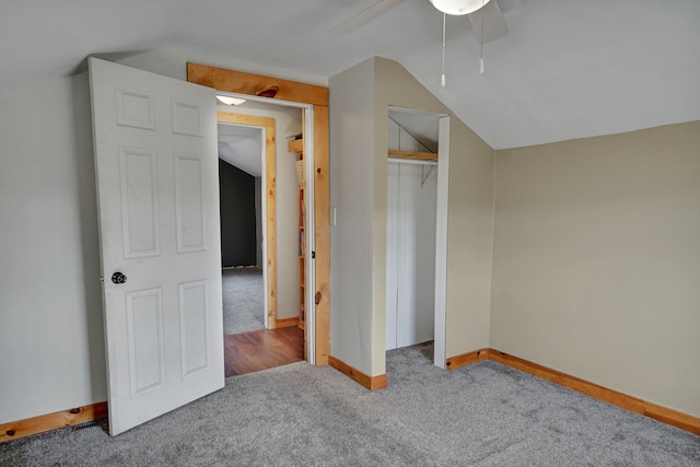 unfurnished bedroom featuring carpet, vaulted ceiling, a closet, baseboards, and ceiling fan