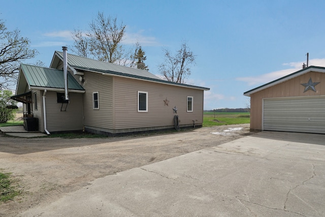 view of home's exterior with metal roof, a chimney, cooling unit, and a detached garage