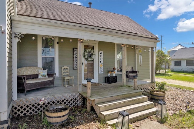 rear view of property featuring covered porch and roof with shingles