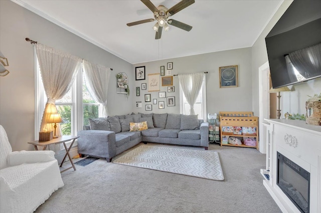 living area featuring carpet, a ceiling fan, and a glass covered fireplace
