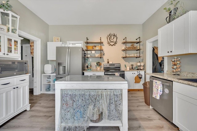 kitchen featuring appliances with stainless steel finishes, light wood finished floors, white cabinets, and glass insert cabinets
