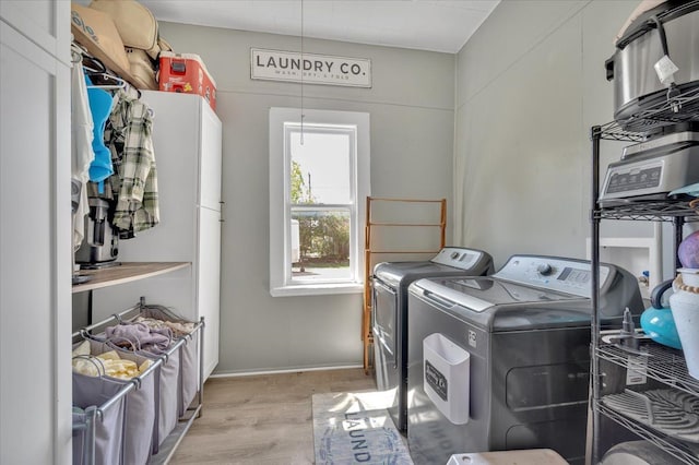 laundry area with separate washer and dryer, cabinet space, light wood-style flooring, and baseboards