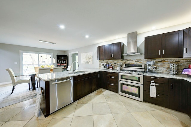 kitchen featuring wall chimney range hood, stainless steel appliances, a sink, decorative backsplash, and recessed lighting