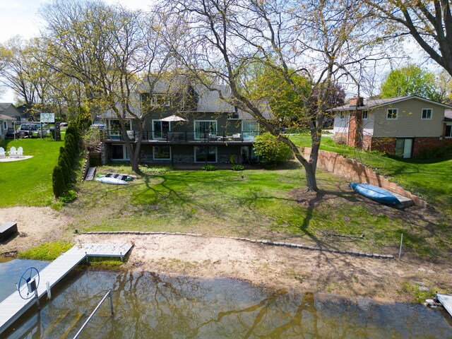 back of house featuring a yard, a water view, and a residential view
