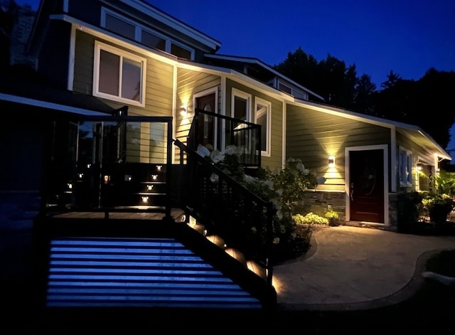 back of house at twilight featuring stairway and a patio area