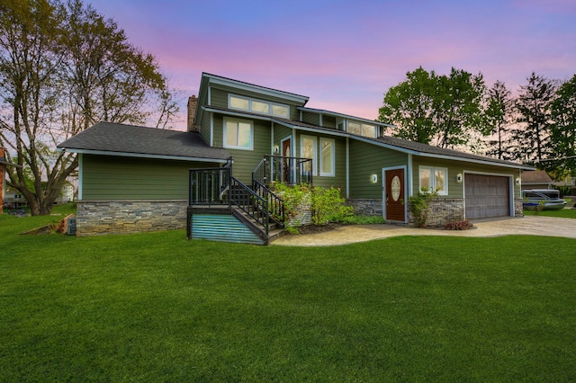 view of front facade with a garage, concrete driveway, a front yard, and stone siding