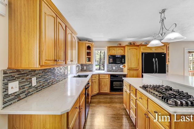 kitchen featuring black appliances, a sink, backsplash, and glass insert cabinets