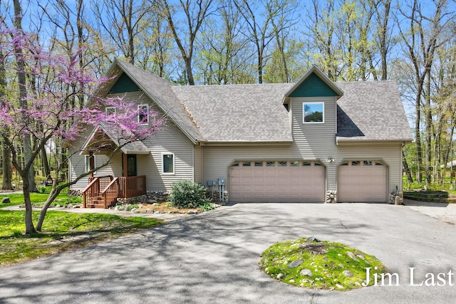 view of front of house featuring asphalt driveway, an attached garage, and roof with shingles