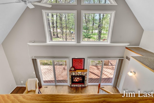 living room featuring vaulted ceiling, plenty of natural light, wood finished floors, a ceiling fan, and a fireplace
