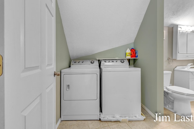laundry room with washer and dryer, a textured ceiling, light tile patterned flooring, and baseboards
