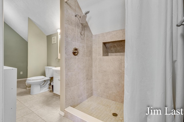full bath featuring lofted ceiling, a tile shower, toilet, tile patterned floors, and vanity
