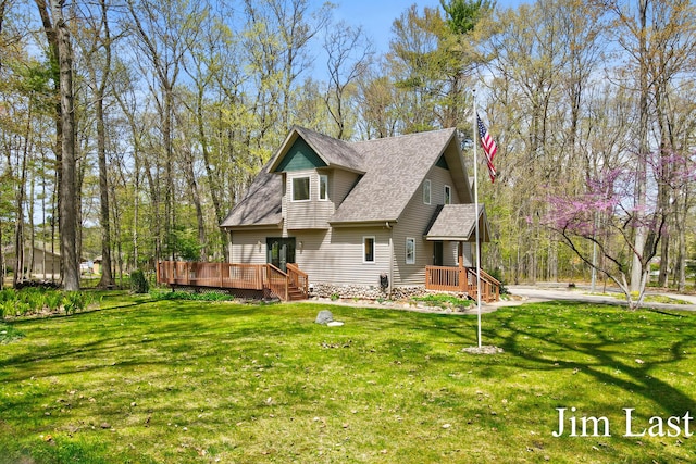 rear view of house featuring roof with shingles, a wooden deck, and a yard