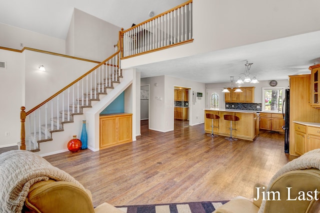 living area featuring light wood-type flooring, baseboards, stairway, and a high ceiling