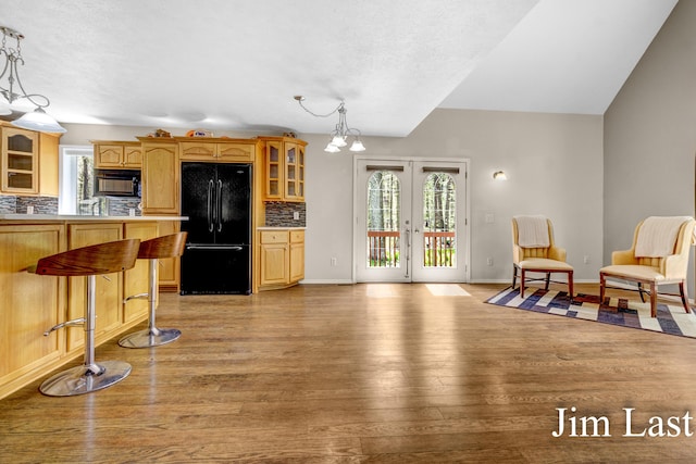 kitchen with black appliances, decorative backsplash, glass insert cabinets, healthy amount of natural light, and vaulted ceiling