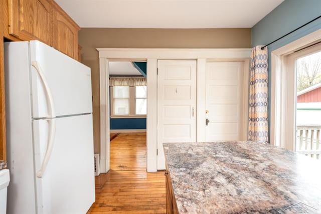 2152 6th St, Bay City, MI 48706 - kitchen with freestanding refrigerator, light wood-type flooring, light stone countertops, and brown cabinets