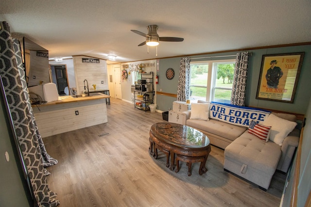 11930 State Rd, Cadillac, MI 49601 - living room featuring wood finished floors, a ceiling fan, crown molding, a textured ceiling, and baseboards