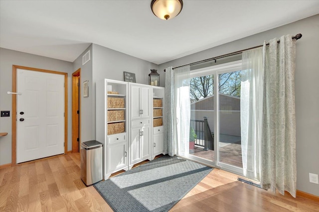doorway to outside with light wood-type flooring and baseboards