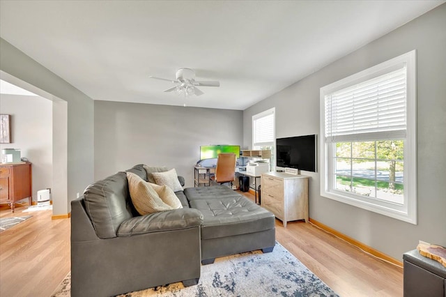 living room with light wood-style floors, a ceiling fan, baseboards, and a desk