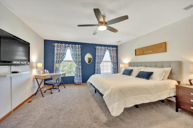 carpeted bedroom with an office area, baseboards, and ceiling fan