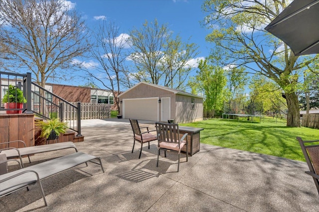 view of patio featuring a garage, a trampoline, an outbuilding, and stairway