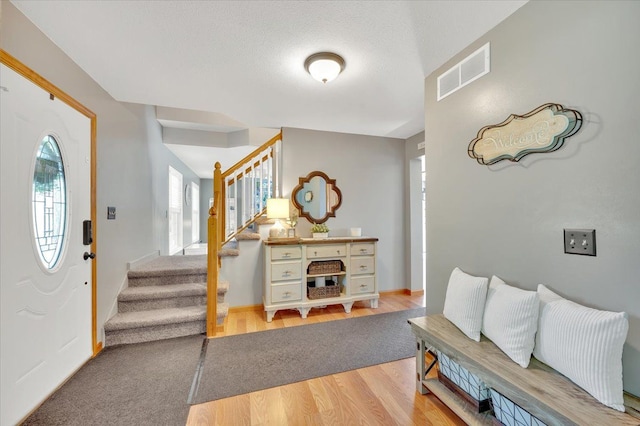 entrance foyer with stairs, wood finished floors, and baseboards