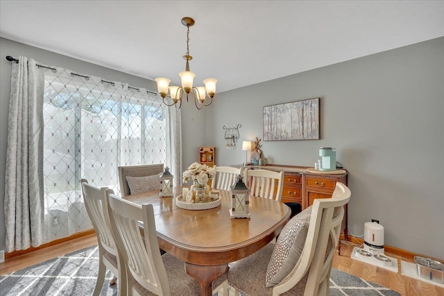 dining space with a chandelier, wood finished floors, and baseboards