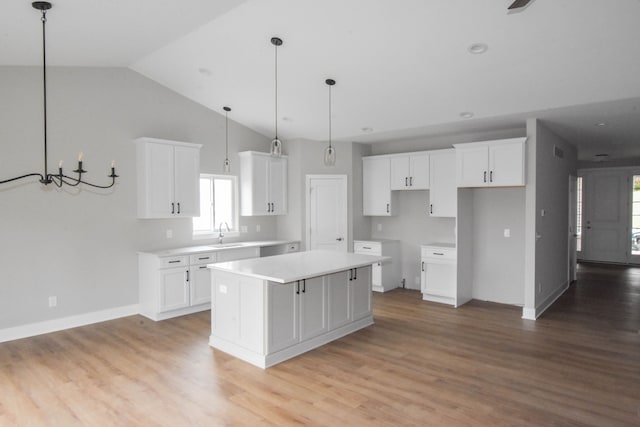 kitchen featuring a sink, a center island, white cabinetry, light wood-style floors, and vaulted ceiling