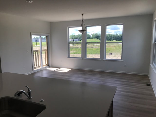 unfurnished dining area featuring dark wood-type flooring, a sink, recessed lighting, and baseboards