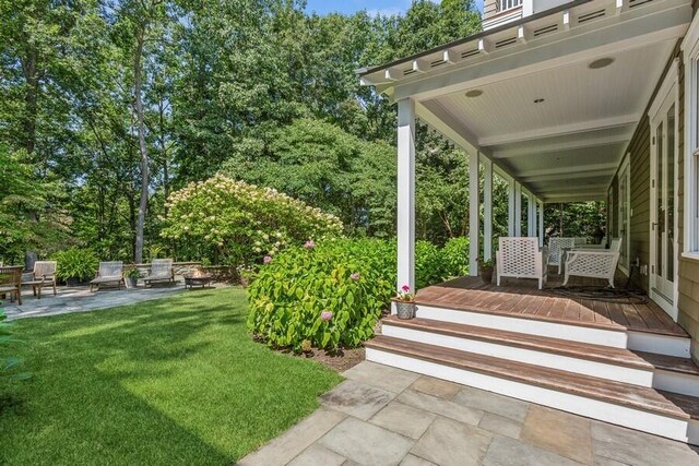 view of green lawn featuring view of scattered trees and a patio area