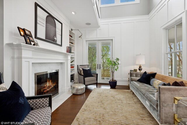 living area featuring a decorative wall, plenty of natural light, a fireplace with flush hearth, and dark wood finished floors