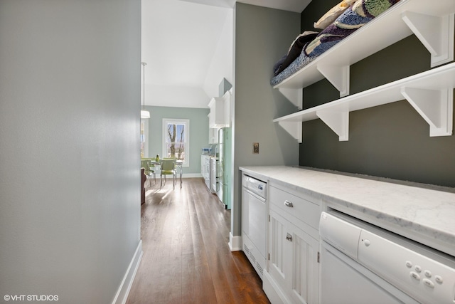 hallway featuring dark wood finished floors, baseboards, and vaulted ceiling