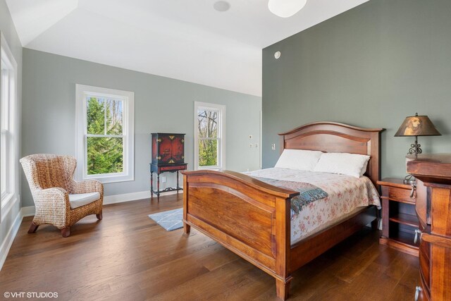 bedroom featuring wood finished floors, baseboards, and lofted ceiling