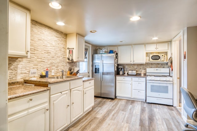321 N Norman St, Barryton, MI 49305 - kitchen with white appliances, backsplash, a sink, light wood-type flooring, and white cabinets
